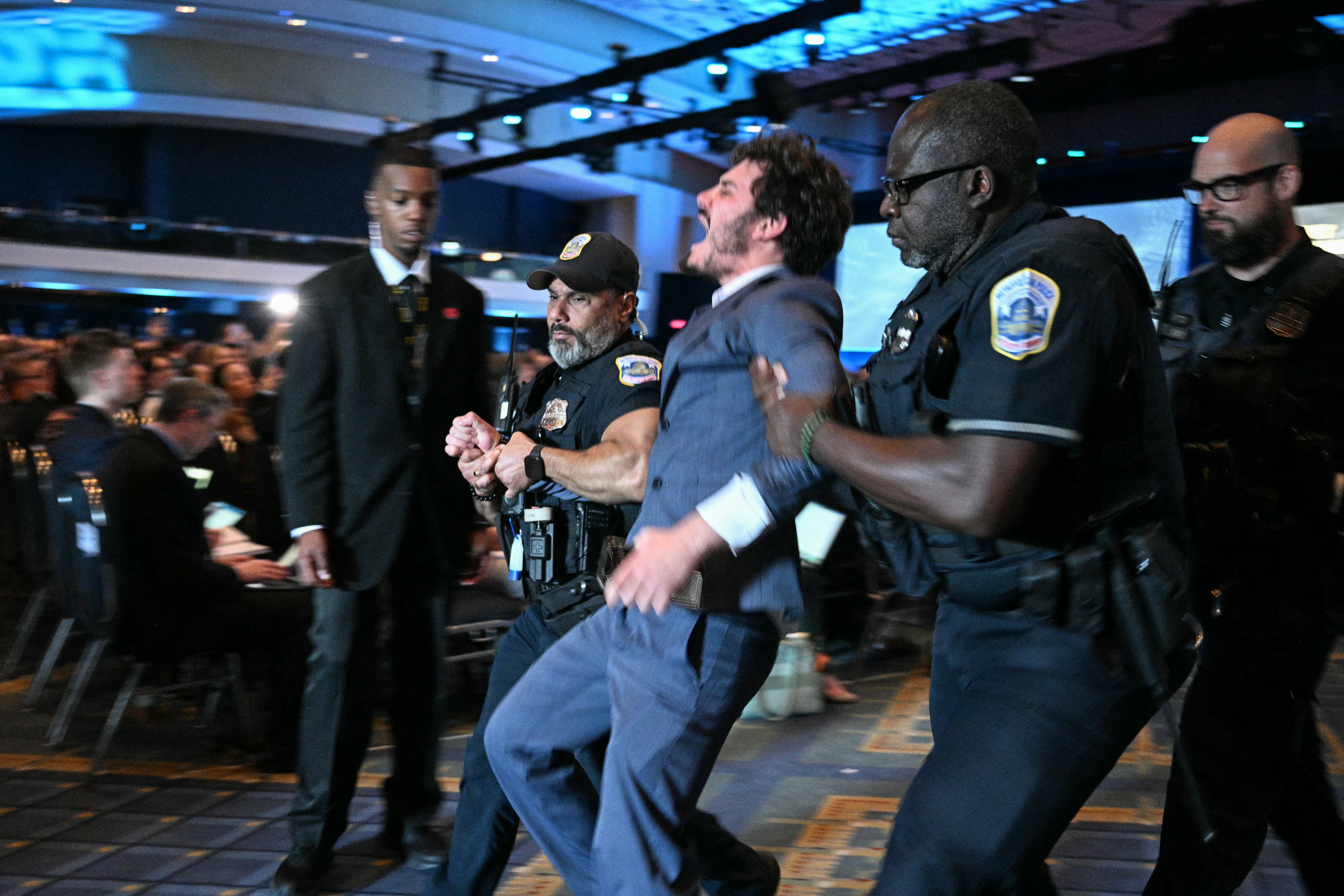 A protester is hauled out of the AUSA panel by police
